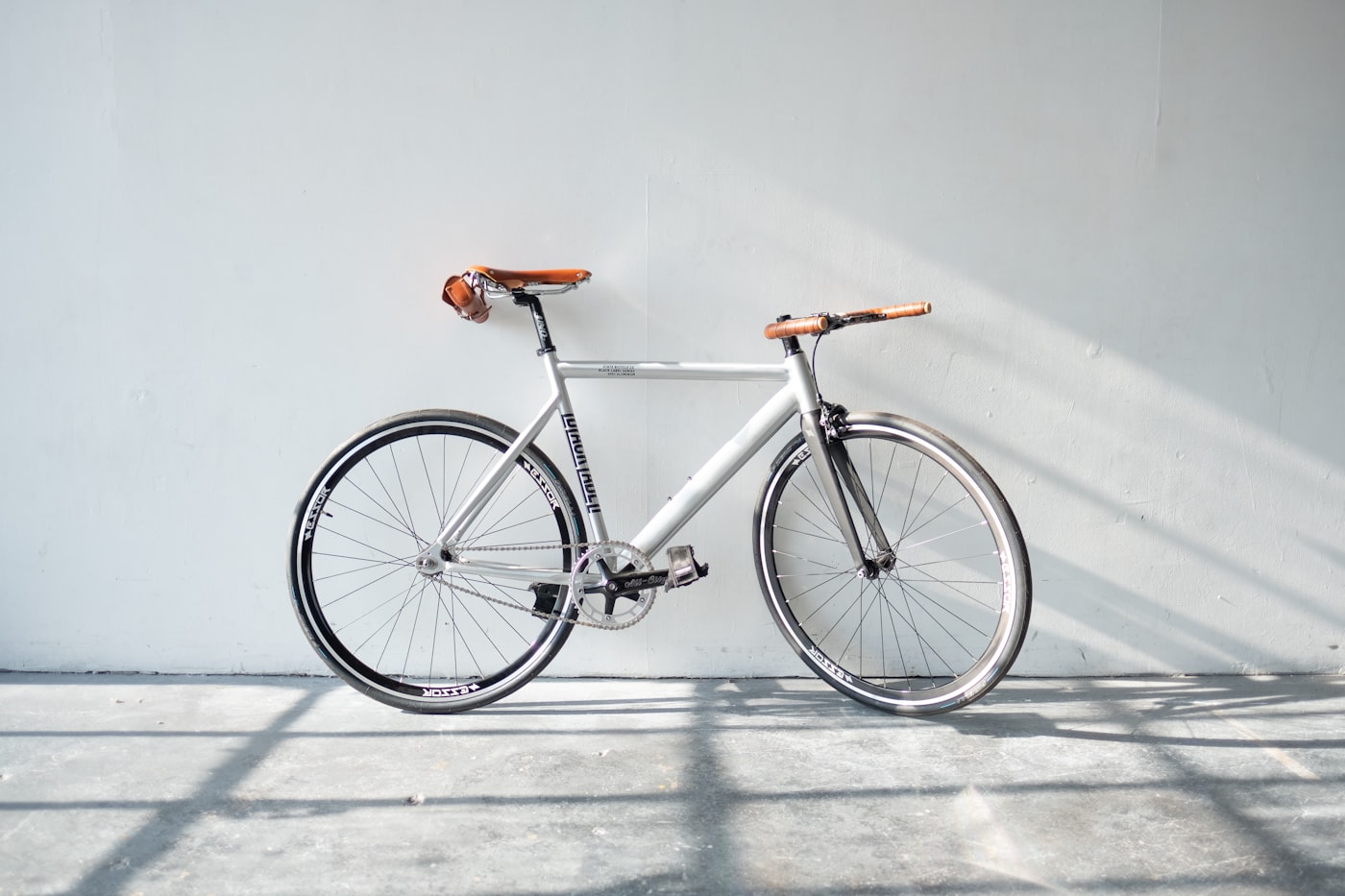 Silbernes Fahrrad mit braunem Ledersattel in hellem Raum