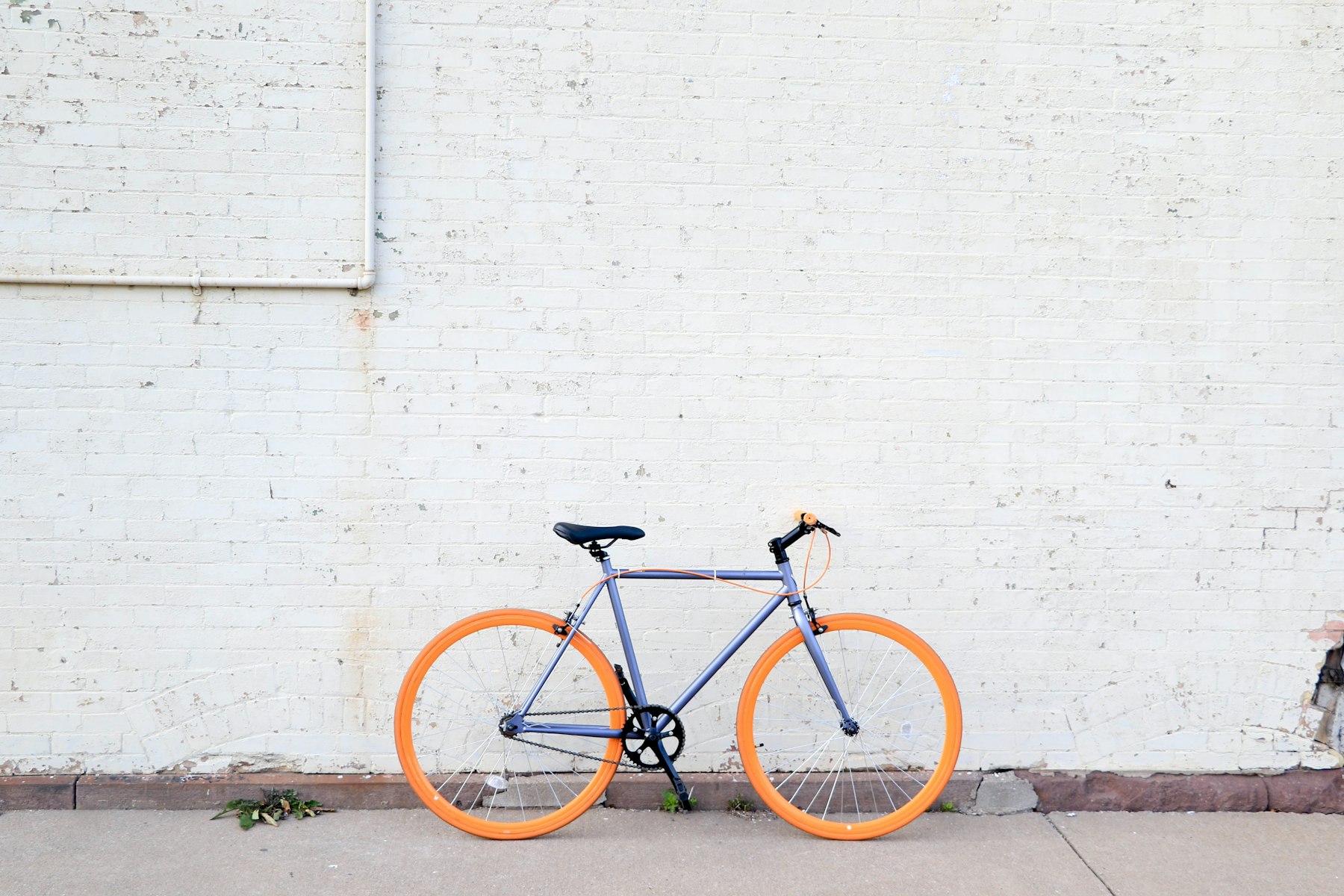 Fahrrad mit leuchtend orangen Felgen vor weißer Backsteinwand